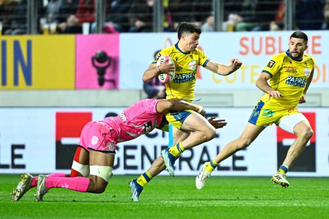 Clermont's Argentine wing Bautista Delguy (C) is tackled by Stade Français' French lock Pierre-Henri Azagoh (L) as he runs with the ball during the French Tot's French centre Léon Darricarrère p14 rugby union match between Stade Francais Paris and ASM Clermont Auvergne at the Jean-Bouin Stadium in Paris on March 29, 2026. (Photo by JULIEN DE ROSA / AFP)