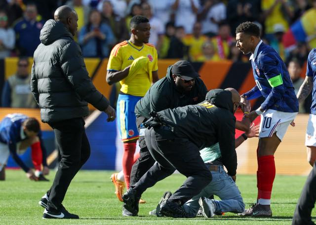 France's forward #10 Kylian Mbappe assists a fan who jumped onto the field to greet him as he's restrained by security at the end of a friendly football match between Colombia and France at Northwest Stadium in Landover, Maryland, on March 29, 2026. (Photo by FRANCK FIFE / AFP)