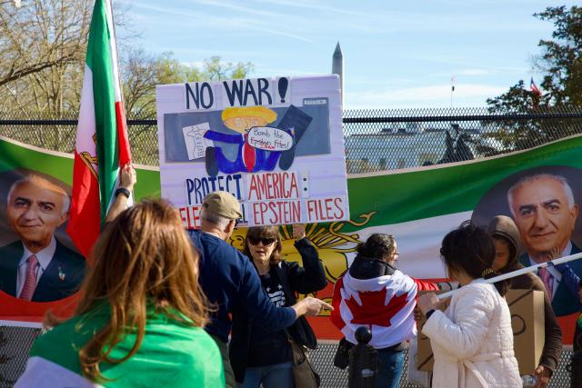 A counter-protester holds up a sign reading "no war" as demonstrators hold a banner with images of Reza Pahlavi, son of the last shah of Iran, near the White House during a rally in support of Iranians' fight for freedom, in Washington, DC, on March 29, 2026. The event, organized by DCProtests4Iran, brought together members of the Iranian diaspora from the Washington, DC metropolitan area and surrounding states. (Photo by Amid FARAHI / AFP)