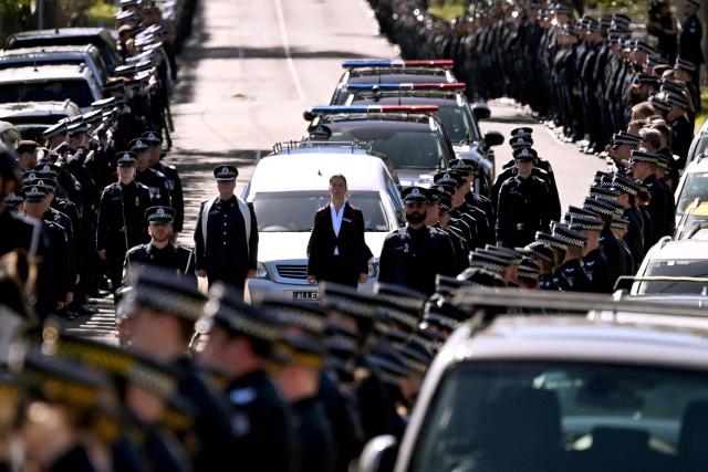 (FILES) A police guard of honour salutes as the coffin of Senior Constable Vadim de Waart-Hottart, one of two officers shot dead by a fugitive gunman, is transported in a funeral procession in Melbourne on September 5, 2025. Australian police said March 30, 2026 they shot dead a fugitive gunman wanted for killing two officers, ending a seven-month manhunt for one of the country's most-wanted criminals. (Photo by William WEST / AFP)
