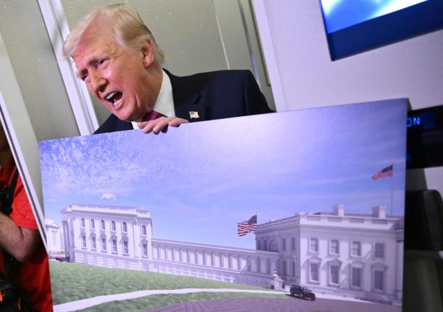 Donald Trump holds a rendering of the East Wing modernization as he speaks to reporters aboard Air Force One en route to Joint Base Andrews, Maryland, on March 29, 2026. US President Donald Trump is returning to White House after spending the weekend at his Mar-A-Lago residence. (Photo by Mandel NGAN / AFP)