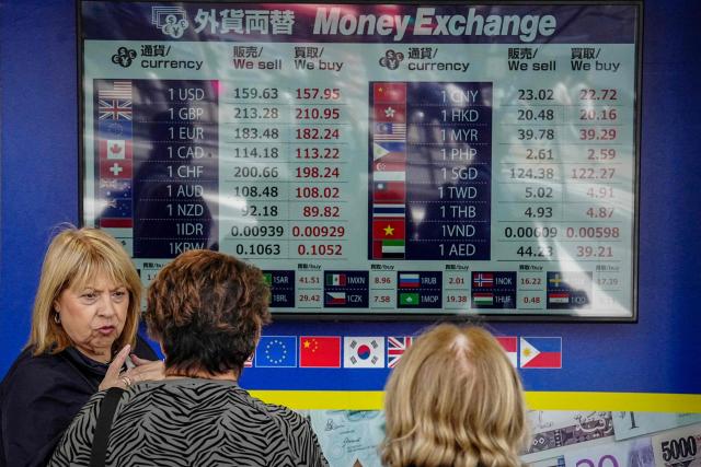 Foreign tourists look at an electronic board displaying foreign exchange rates at a currency exchange shop in Tokyo on March 30, 2026. (Photo by Yuichi YAMAZAKI / AFP)