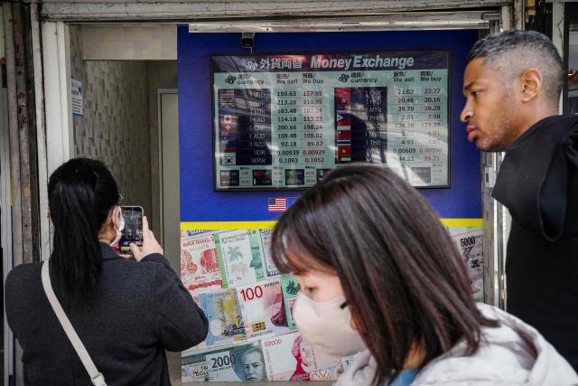 A woman (L) photographs an electronic board displaying foreign exchange rates at a currency exchange shop in Tokyo on March 30, 2026. (Photo by Yuichi YAMAZAKI / AFP)