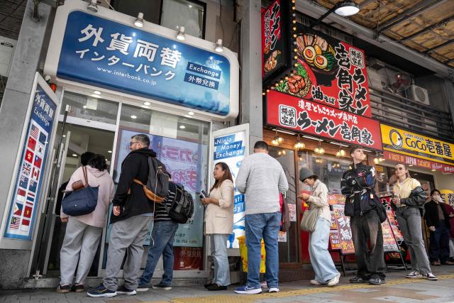 People queue in front of a currency exchange shop in Tokyo on March 30, 2026. (Photo by Yuichi YAMAZAKI / AFP)