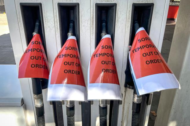 Signs cover petrol bowsers at a closed petrol station in Sydney on March 30, 2026. Australia will halve a tax on fuel to reduce costs for motorists experiencing soaring petrol prices due to war in the Middle East, Prime Minister Anthony Albanese said on March 30, 2026. (Photo by DAVID GRAY / AFP)