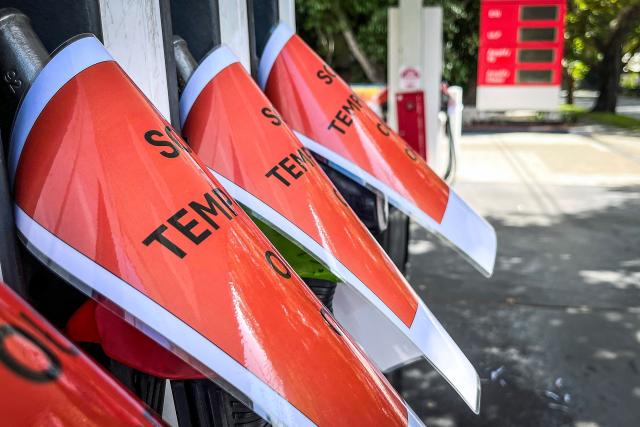 Signs cover petrol bowsers at a closed petrol station in Sydney on March 30, 2026. Australia will halve a tax on fuel to reduce costs for motorists experiencing soaring petrol prices due to war in the Middle East, Prime Minister Anthony Albanese said on March 30, 2026. (Photo by DAVID GRAY / AFP)