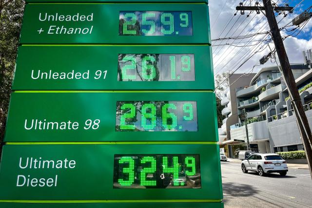 A car passes a sign displaying petrol prices at a petrol station in Sydney on March 30, 2026. Australia will halve a tax on fuel to reduce costs for motorists experiencing soaring petrol prices due to war in the Middle East, Prime Minister Anthony Albanese said on March 30, 2026. (Photo by DAVID GRAY / AFP)