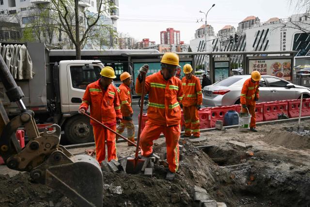 Workers rebuild a sidewalk in Beijing on March 30, 2026. (Photo by Pedro PARDO / AFP)
