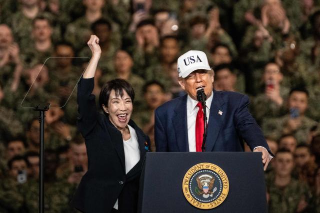 (FILES) Japan's Prime Minister Sanae Takaichi (L) gestures as US President Donald Trump delivers a speech in front of US Navy personnel on board the US Navy's USS George Washington aircraft carrier at the US naval base in Yokosuka on October 28, 2025. (Photo by Philip FONG / AFP)