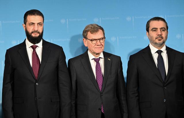 (L to R) Syrian President Ahmed al-Sharaa, German Foreign Minister Johann Wadephul and Syrian Foreign Minister Asaad al-Shibani pose ahead a German-Syrian roundtable meeting on economy at the Foreign Ministry in Berlin on March 30, 2026. Syria's President Ahmed al-Sharaa visits Germany on Monday for talks on the Middle East war, rebuilding his country and Berlin's efforts to send back Syrian refugees. (Photo by RALF HIRSCHBERGER / AFP)