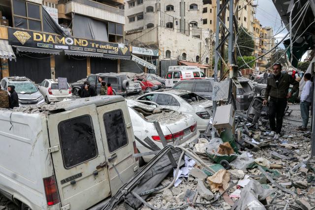People and first-responders walk amidst debris as they gather before a building that was hit by an Israeli airstrike in Beirut’s southern suburbs on March 30, 2026. A strike hit Beirut's southern suburbs on March 30 after Israel issued a warning for people in the Hezbollah stronghold to leave. The strike is the first since March 27 in the area, which is now largely deserted since Israel began frequent attacks against Hezbollah earlier in the month. (Photo by Anwar AMRO / AFP) / 