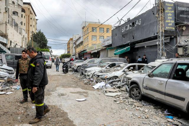 People and first-responders walk amidst debris as they gather before a building that was hit by an Israeli airstrike in Beirut’s southern suburbs on March 30, 2026. A strike hit Beirut's southern suburbs on March 30 after Israel issued a warning for people in the Hezbollah stronghold to leave. The strike is the first since March 27 in the area, which is now largely deserted since Israel began frequent attacks against Hezbollah earlier in the month. (Photo by Anwar AMRO / AFP) / 