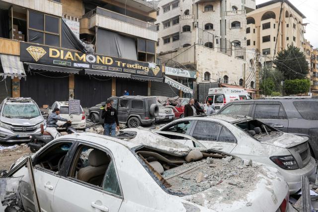 People and first-responders walk amidst debris as they gather before a building that was hit by an Israeli airstrike in Beirut’s southern suburbs on March 30, 2026. A strike hit Beirut's southern suburbs on March 30 after Israel issued a warning for people in the Hezbollah stronghold to leave. The strike is the first since March 27 in the area, which is now largely deserted since Israel began frequent attacks against Hezbollah earlier in the month. (Photo by Anwar AMRO / AFP) / 