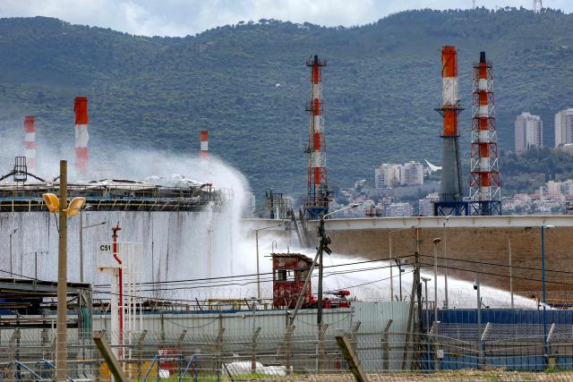 Firefighters attempt to extinguish a fire following a projectile impact on a refinery in Israel's northern city of Haifa on March 30, 2026. Israel and Iran exchanged more missile fire on March 30 as concerns that the US might escalate the Middle East conflict by launching ground raids against the Islamic republic's Gulf islands sent oil prices soaring. (Photo by Jack GUEZ / AFP)