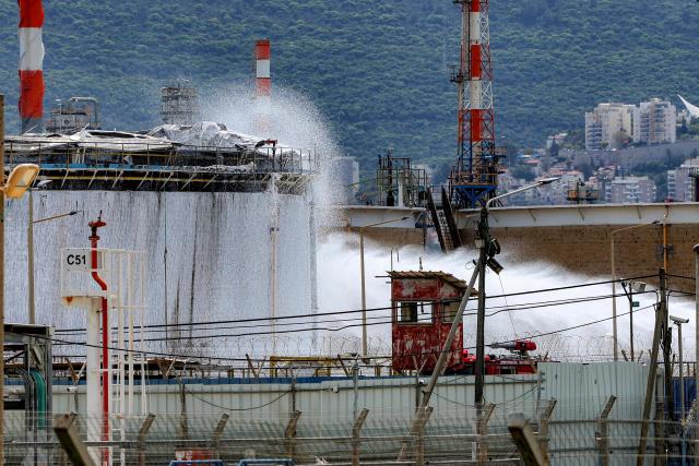 Firefighters attempt to extinguish a fire following a projectile impact on a refinery in Israel's northern city of Haifa on March 30, 2026. Israel and Iran exchanged more missile fire on March 30 as concerns that the US might escalate the Middle East conflict by launching ground raids against the Islamic republic's Gulf islands sent oil prices soaring. (Photo by Jack GUEZ / AFP)
