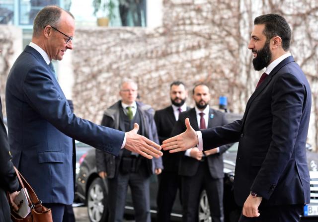 German Chancellor Friedrich Merz (L) welcomes Syrian President Ahmed al-Sharaa at the Chancellery in Berlin on March 30, 2026. Syria's President Ahmed al-Sharaa visits Germany on Monday for talks on the Middle East war, rebuilding his country and Berlin's efforts to send back Syrian refugees. (Photo by John MACDOUGALL / AFP)