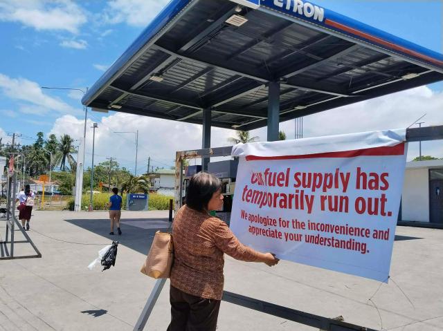 A pedestrian reads a sign at a petrol station in Tacloban City, Leyte province, central Philippines on March 30, 2026. The Philippines' sole oil refinery has secured nearly 2.5 million barrels of Russian crude out of "extreme necessity", a stock exchange filing revealed on March 30, as the country seeks to replenish fast-dwindling fuel reserves. (Photo by Marlon TANO / AFP)