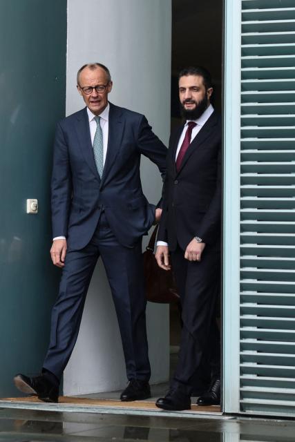 German Chancellor Friedrich Merz walks with Syrian President Ahmed al-Sharaa at the terrace of the Chancellery ahead of their bilateral talks on March 30, 2026 in Berlin. Syria's President Ahmed al-Sharaa visits Germany on Monday for talks on the Middle East war, rebuilding his country and Berlin's efforts to send back Syrian refugees. (Photo by Nadja Wohlleben / POOL / AFP)