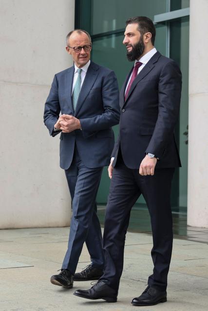 German Chancellor Friedrich Merz walks with Syrian President Ahmed al-Sharaa at the terrace of the Chancellery ahead of their bilateral talks on March 30, 2026 in Berlin. Syria's President Ahmed al-Sharaa visits Germany on Monday for talks on the Middle East war, rebuilding his country and Berlin's efforts to send back Syrian refugees. (Photo by Nadja Wohlleben / POOL / AFP)
