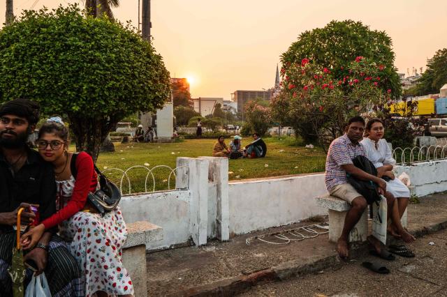 People sit outside the Central Railway Station as the sun sets in Yangon on March 29, 2026. (Photo by ANTHONY WALLACE / AFP)