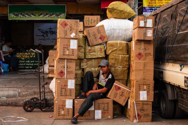 A worker sits amongst boxes of packaged goods in Yangon on March 29, 2026. (Photo by ANTHONY WALLACE / AFP)