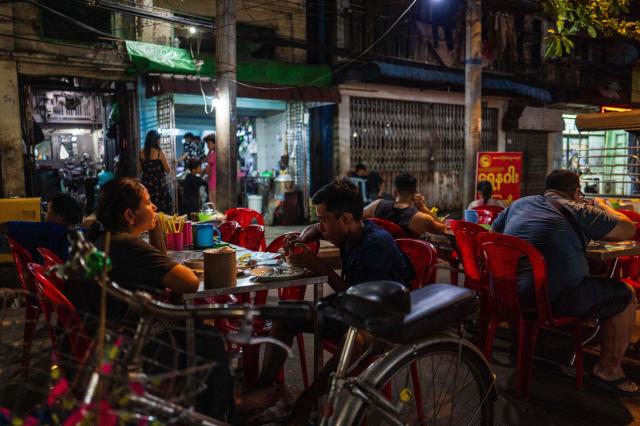 Diners eat food along a street outside a restaurant in Yangon on March 29, 2026. (Photo by ANTHONY WALLACE / AFP)