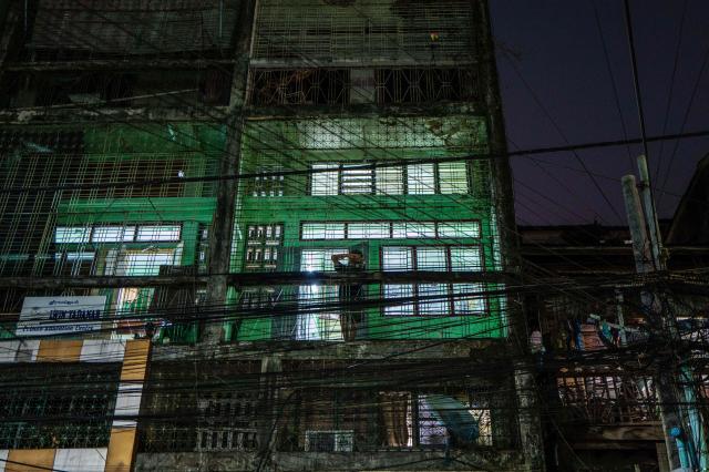 A person leans against a metal grill on their balcony in a residential building in Yangon on March 29, 2026. (Photo by ANTHONY WALLACE / AFP)