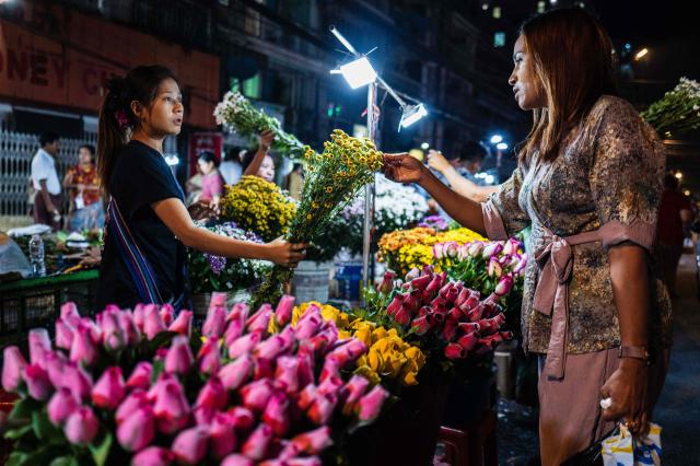 A woman buys flowers from a florist at a street market in Yangon on March 29, 2026. (Photo by ANTHONY WALLACE / AFP)