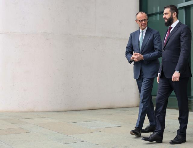 German Chancellor Friedrich Merz walks with Syrian President Ahmed al-Sharaa, on the terrace of the Chancellery ahead of their bilateral talks on March 30, 2026 in Berlin. Syria's President Ahmed al-Sharaa visits Germany on Monday for talks on the Middle East war, rebuilding his country and Berlin's efforts to send back Syrian refugees. (Photo by Nadja Wohlleben / POOL / AFP)