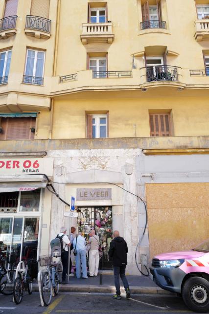 People pay tribute beside flowers laid outside the building where the late reality TV star Loana lived in Nice, southeastern France, on March 30, 2026. France’s first reality TV star Loana, 48, was found dead at her home in Nice on March 25, 2026. (Photo by Valery HACHE / AFP)