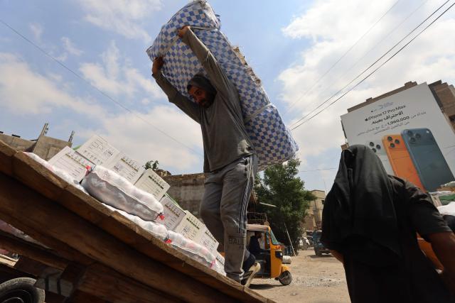 Workers load goods onto trucks at a transport garage in the Maidan area of central Baghdad on March 30, 2026. As cargo ships remain unable to enter Iraq's port of Umm Qasr along the Gulf due to the closure of the Hormuz Strait due to the war between Iran and the US and Israel, Iraq's trade has been severely impacted negatively, depending mainly now on overland transport. (Photo by AHMAD AL-RUBAYE / AFP)