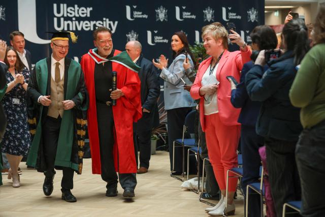 Hollywood actor and former California state governor, Arnold Schwarzenegger, walks with Vice-Chancellor of Ulster University, Professor Paul Bartholomew following a ceremony to receive an honorary doctorate from Ulster University in Belfast, Northern Ireland, on March 30, 2026. (Photo by Paul Faith / AFP)