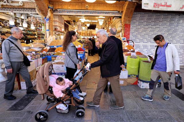 People walk past shops at the Grand Bazaar in Tehran on March 30, 2026. US President Donald Trump pushed concerns about surging world prices aside on March 30 and threatened to destroy Iran's oil wells, power plants and main export terminal if Tehran does not quickly accept a peace deal. (Photo by ATTA KENARE / AFP) / 