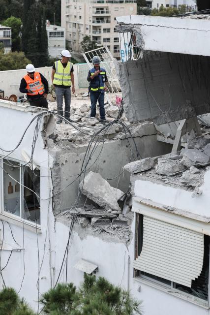 Workers assess the damage to an apartment after an Iranian strike hit a residential neighbourhood in Haifa, on March 30, 2026. The Middle East was sparked by joint US-Israeli strikes on Iran that triggered a wave of retaliatory missile and drone attacks against Israel and several other countries in the region. (Photo by Jack GUEZ / AFP) / 