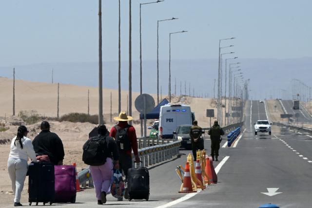 (FILES) Migrants walk back to Chile after they were not allowed to enter Peru, near de Cachalluta border crossing, about 25 km north of Arica, Chile, on November 30, 2025. Chile's new government led by far-right politician José Antonio Kast has halted the regularisation of 182,000 migrants in Chile, a process initiated by the previous administration of left-wing President Gabriel Boric, the Immigration Service told AFP on March 30, 2026. (Photo by Rodrigo ARANGUA / AFP)