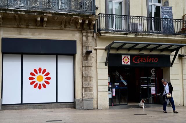 (FILES) A woman and her dog walk past a Casino shop in Beziers, southern France on April 3, 2025. Casino deepened its net loss to 402 million euros in 2025, due in part to a major social plan launched in 2024, but the retailer said on March 30, 2026, its profitability improves "significantly" as debt-restructuring negotiations continue. (Photo by GABRIEL BOUYS / AFP)