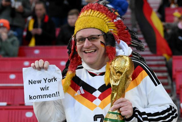 A Germany fan wearing a costume poses with a trophy and a letter reading 'New York we are coming' prior to the international friendly football match between Germany and Ghana at the MHP Arena in Stuttgart, southwestern Germany on March 30, 2026. (Photo by THOMAS KIENZLE / AFP)