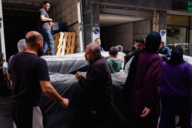 Displaced people receive mattresses at a humanitarian distribution point in Beirut on March 30, 2026. Israel renewed its bombardment of Beirut's southern suburbs on March 30 while continuing air strikes on Lebanon's south, one of which targeted an army checkpoint and killed a soldier. Lebanon was pulled into the Middle East conflict when Tehran-backed armed group Hezbollah fired rockets at Israel on March 2 in revenge for the killing of Iran's supreme leader, the opening salvo in the US-Israeli war against the Islamic republic. (Photo by Dimitar DILKOFF / AFP)