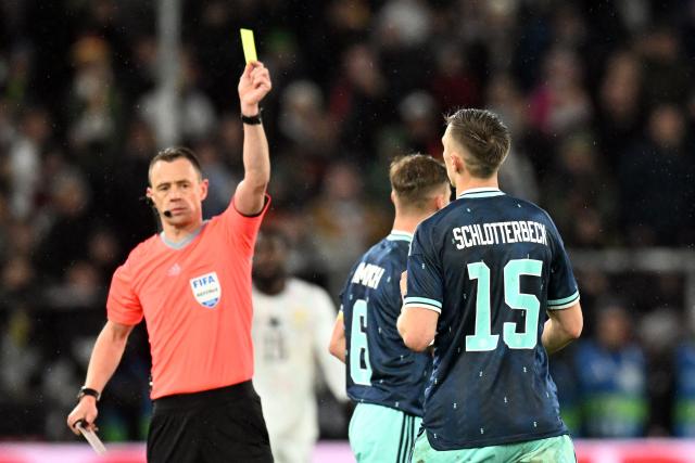 English referee Stuart Attwell (L) shows the yellow card to Germany's defender #15 Nico Schlotterbeck (R) during the international friendly football match between Germany and Ghana in Stuttgart, southwestern Germany on March 30, 2026. (Photo by THOMAS KIENZLE / AFP)