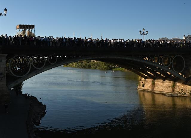 The image of the Virgin of the San Gonzalo brotherhood crosses a bridge during the Holy Monday procession in Seville, Spain, on March 30, 2026. Christian believers around the world mark Holy Week in celebration of the crucifixion and resurrection of Jesus Christ. (Photo by CRISTINA QUICLER / AFP)