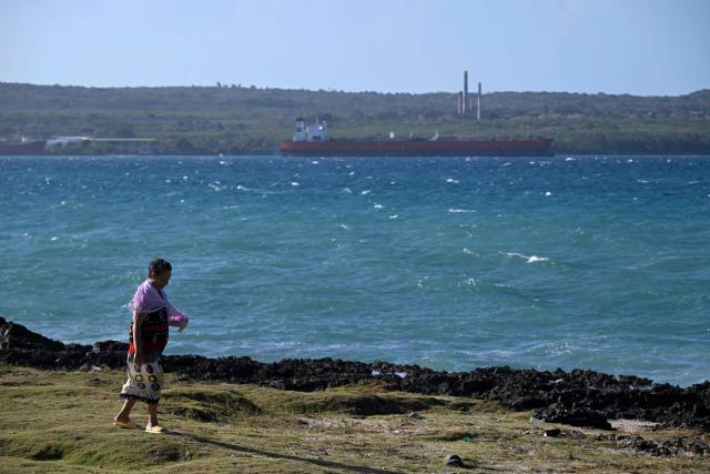 A woman walks on the coastline as an oil tanker ship sails on Matanzas Bay, Cuba on March 30, 2026. US President Donald Trump said on March 29, 2026, that Moscow could send oil to Cuba despite Washington's de facto fuel blockade, as a Russian tanker was expected to deliver some much-needed crude to the crisis-hit island. The Anatoly Kolodkin, which is carrying 730,000 barrels of crude, was off northeast Cuba on the evening of March 29 and is expected to dock in the western port of Matanzas by March 31, according to shipping tracker MarineTraffic. (Photo by Yamil LAGE / AFP)