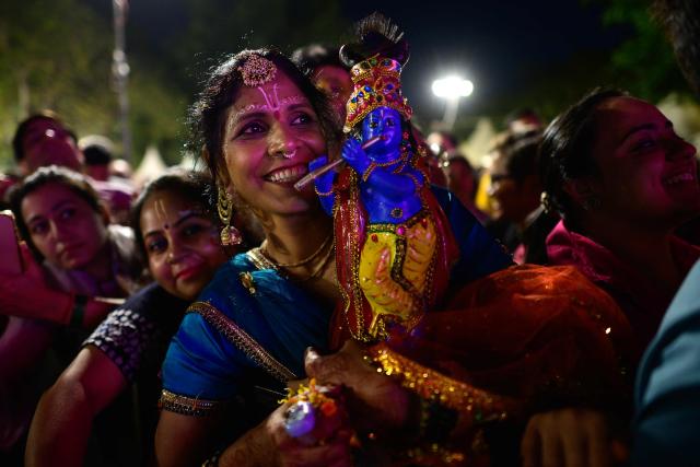 (FILES) A reveller holding an idol of Lord Krishna enjoys Hindu spiritual songs called 'Bhajans' during the Sanatan Journey devotional music festival at the iconic Purana Qila in New Delhi on March 1, 2026. In India's capital, Hindu "bhajan clubbing" is electrifying nightlife, with revellers dancing to traditional devotional songs reimagined through guitars and pounding drumbeats, transforming public venues into spiritual hangouts. (Photo by Manan VATSYAYANA / AFP)