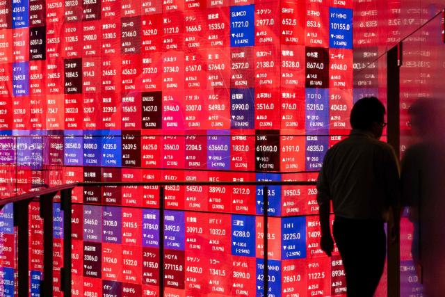 A man passes an electronic quotation board displaying the Nikkei 225 stock prices on the Tokyo Stock Exchange in Tokyo on March 31, 2026. (Photo by Kazuhiro NOGI / AFP)