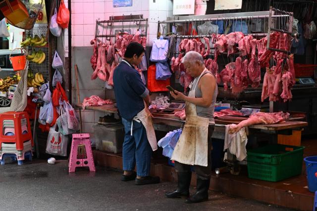 A butcher waits for customers on a market street in Hong Kong on March 31, 2026. (Photo by Peter PARKS / AFP)