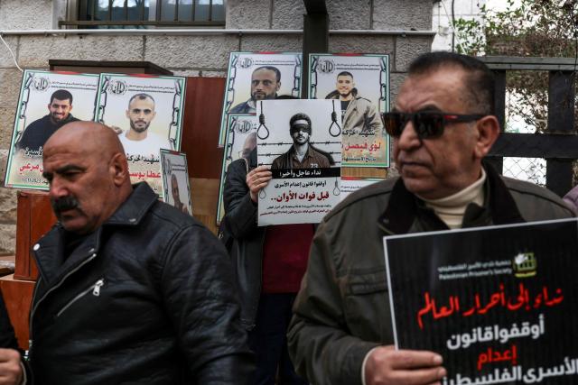 Protesters hold placards outside the Red Cross offices in Ramallah, in the Israeli-occupied West Bank, on March 31, 2026, during a rally against a bill approved by Israel's parliament that would allow the execution of Palestinians convicted on terror charges for deadly attacks. Israel's parliament approved a bill on March 30, that would allow the execution of Palestinians convicted on terror charges for deadly attacks, a move that has been criticised as discriminatory and immediately drew a court challenge. (Photo by Zain JAAFAR / AFP)