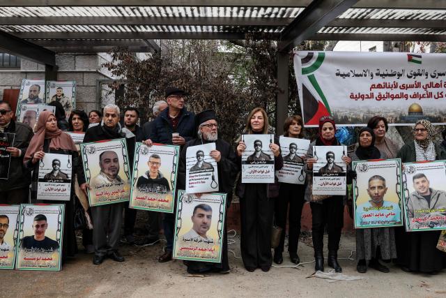 Protesters hold placards outside the Red Cross offices in Ramallah, in the Israeli-occupied West Bank, on March 31, 2026, during a rally against a bill approved by Israel's parliament that would allow the execution of Palestinians convicted on terror charges for deadly attacks. Israel's parliament approved a bill on March 30, that would allow the execution of Palestinians convicted on terror charges for deadly attacks, a move that has been criticised as discriminatory and immediately drew a court challenge. (Photo by Zain JAAFAR / AFP)