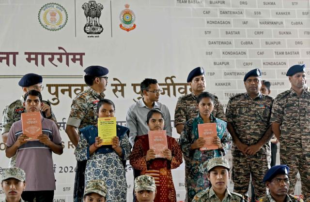 Security personnel pose with Maoist rebels and fighters upon their surrender, at a police facility in Dantewada in Chhattisgarh state's Bastar division on March 31, 2026. India on March 30, declared the country free of the Maoist insurgency, fulfilling a long-standing deadline to defeat the decades-long rebellion. (Photo by Shammi MEHRA / AFP)