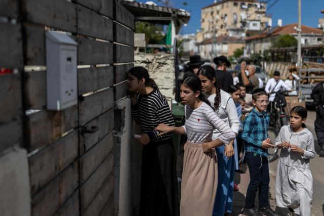 Ultra-Orthodox Jews peer through a fence to look at the damage at a site hit during an Iranian strike over Bnei Brak in central Israel on March 31, 2026. Iran fired missiles across the Middle East on March 31 as its capital was hit by fresh explosions, after US President Donald Trump threatened the country's key oil export hub, power stations and desalination plants. (Photo by Ilia YEFIMOVICH / AFP) / 