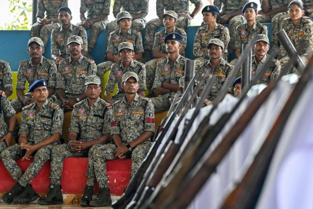 Security personnel sit next to weapons seized from Maoist rebels and fighters upon their surrender at a police facility in Dantewada in Chhattisgarh state's Bastar division on March 31, 2026. Indian police on March 31 displayed large caches of arms and ammunition seized from Maoist rebels, a day after officials declared the six-decade-long insurgency was over following a sustained security crackdown. (Photo by Shammi MEHRA / AFP)