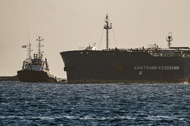 A tug boat guides the Russian oil tanker Anatoly Kolodkin as it arrives at the oil terminal in the port of Matanzas, northwestern Cuba, early on March 31, 2026. The Anatoly Kolodkin, a tanker under US sanctions carrying 730,000 barrels of crude, is set to deliver the first crude shipment to Cuba since January after Washington gave the crisis-hit island a reprieve from an effective fuel blockade. (Photo by Yamil LAGE / AFP)